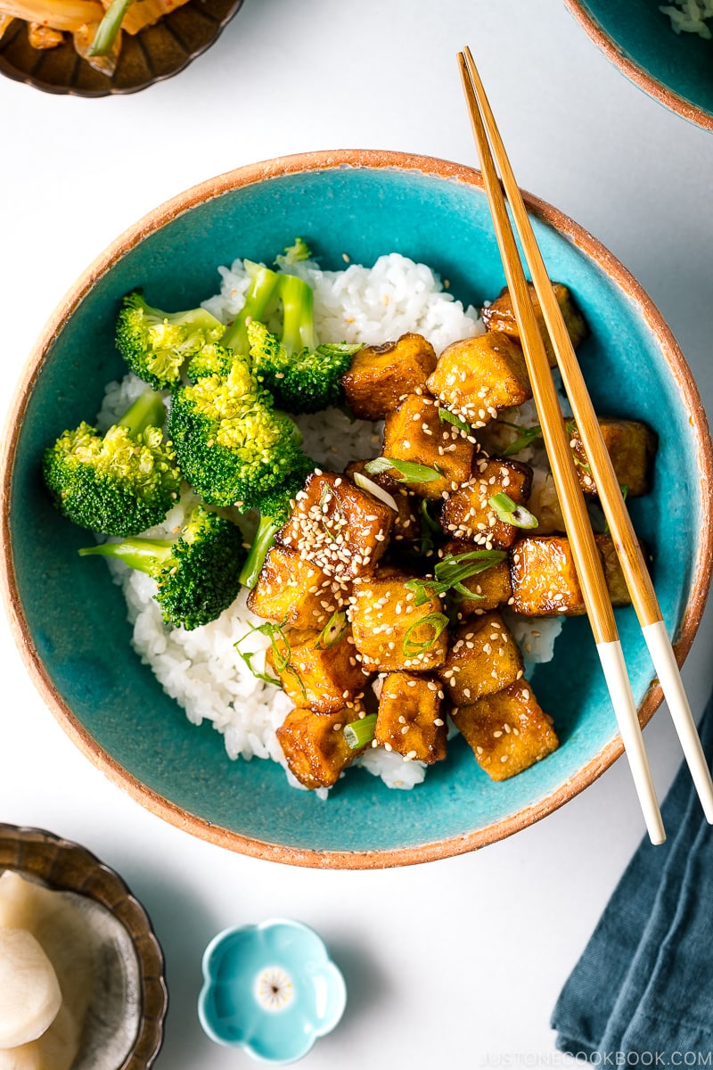 A taquoise bowl containing teriyaki tofu and broccoli over steamed rice.