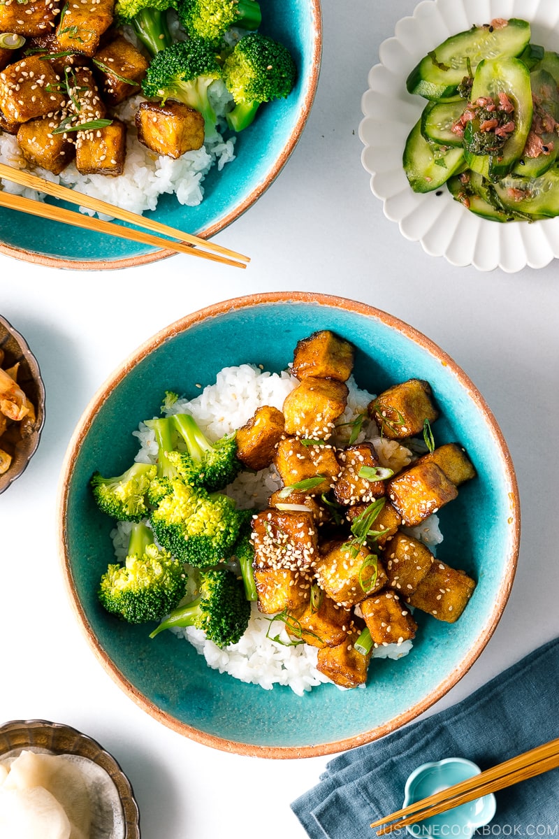 A taquoise bowl containing teriyaki tofu and broccoli over steamed rice.