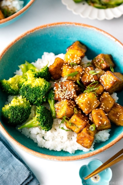 A taquoise bowl containing teriyaki tofu and broccoli over steamed rice.