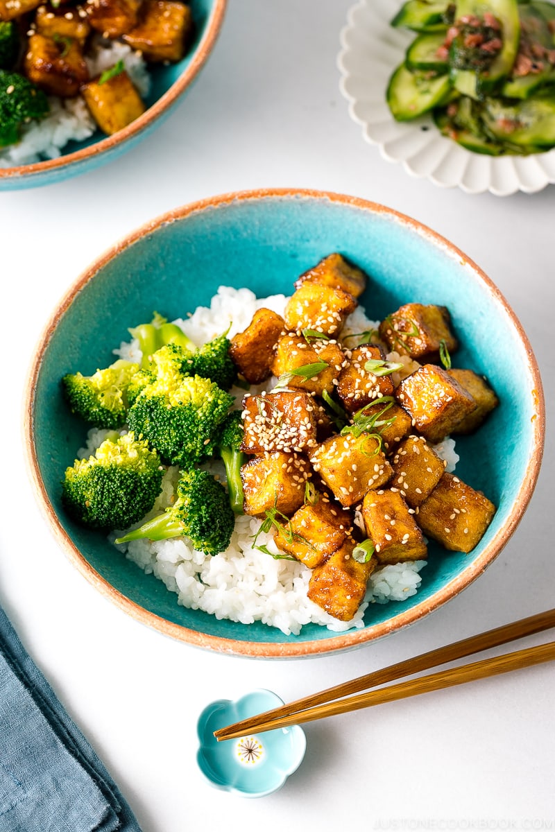 A taquoise bowl containing teriyaki tofu and broccoli over steamed rice.