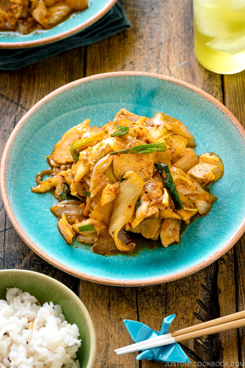 A Japanese ceramic plate containing Pork Kimchi Stir-Fry called Buta Kimchi. It's served with steamed rice.