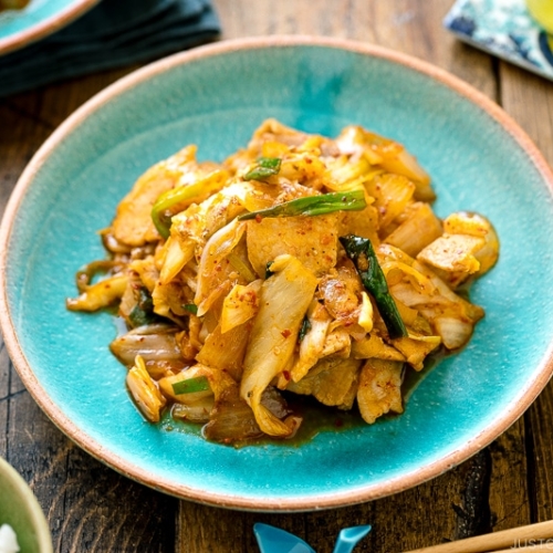 A Japanese ceramic plate containing Pork Kimchi Stir-Fry called Buta Kimchi. It's served with steamed rice.