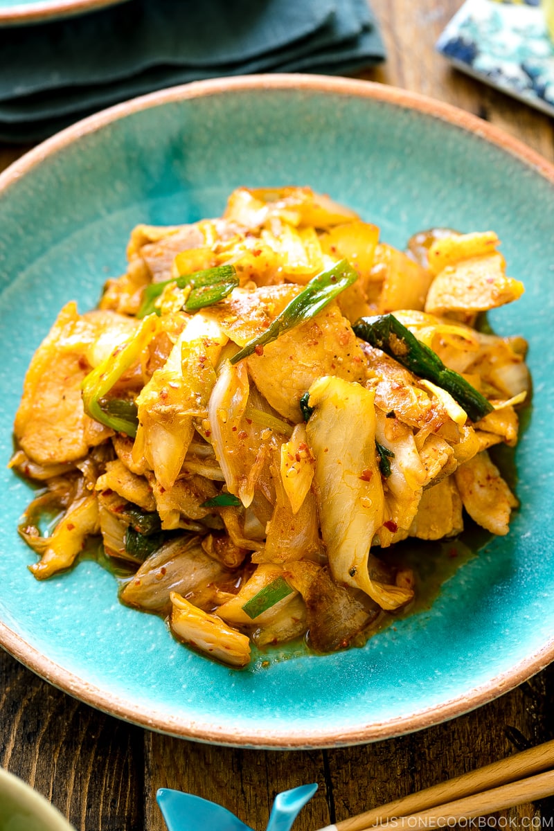 A Japanese ceramic plate containing Pork Kimchi Stir-Fry called Buta Kimchi. It's served with steamed rice.