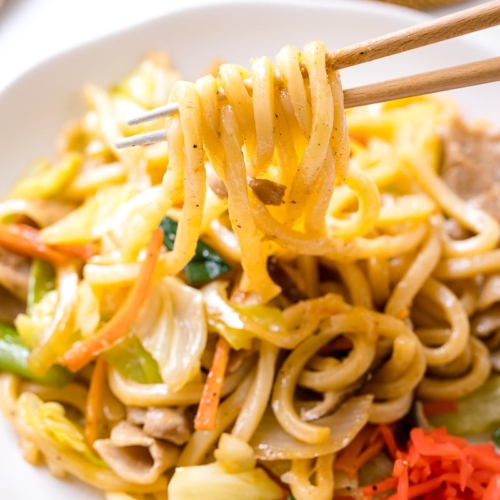 Yaki Udon (Japanese Stir-Fried Udon Noodles) being pulled out with chopsticks.