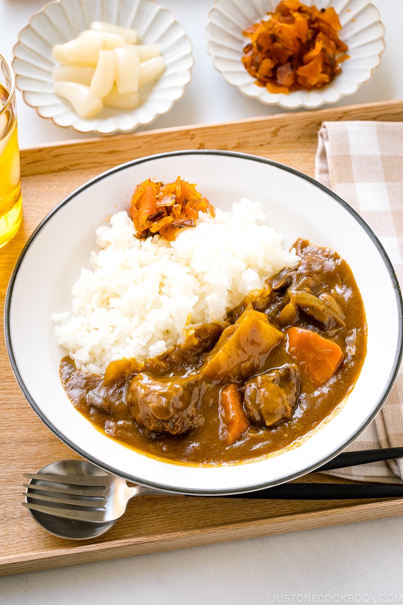 A Japanese plate containing steamed rice and Japanese beef curry garnished with pickles.