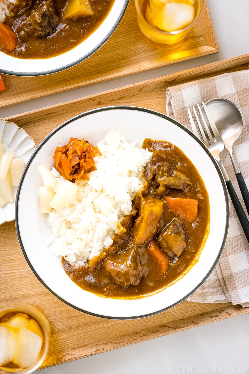 A Japanese plate containing steamed rice and Japanese beef curry garnished with pickles.