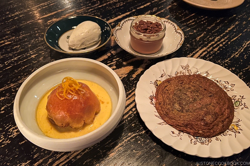 large chocolate chip cookie and desserts on a wood table