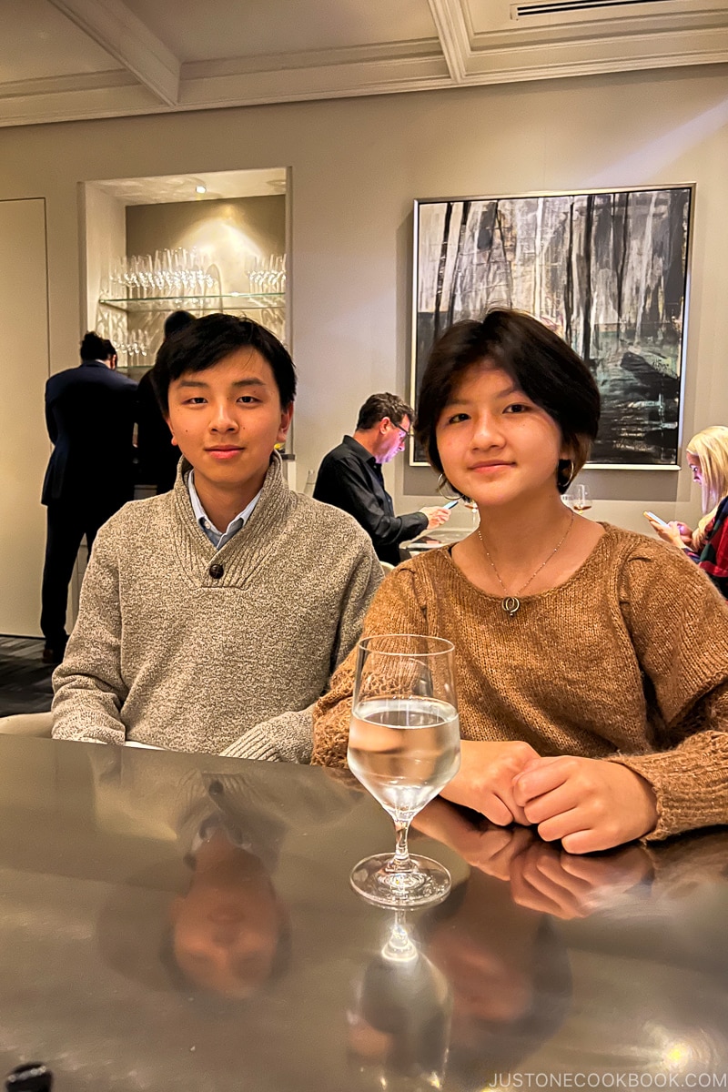 a boy and a girl sitting at a stainless steel table