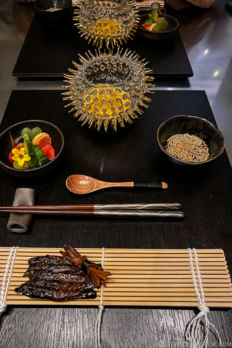 table setting with a glass bowl at the top and sushi mat at the bottom
