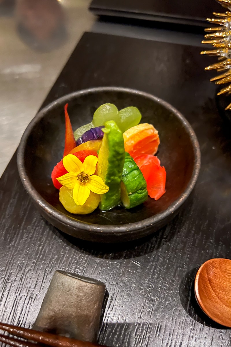 preserved vegetables in a wood bowl on black placemat