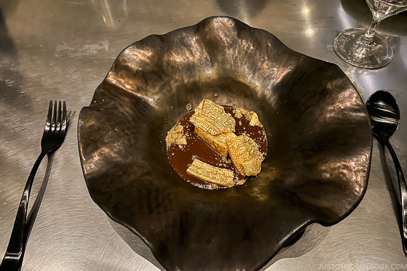 gold crusted squash in mole on a curved plate