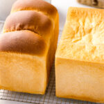 Two loaves of Japanese milk bread (flat-topped and round-topped) on a wire rack.