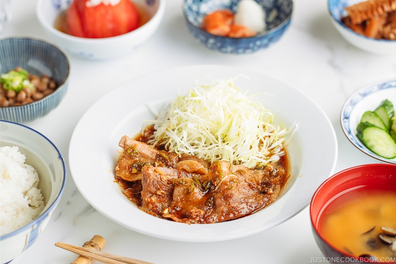 A plate containing Pan-Fried Ginger Pork Belly along with shredded cabbage.