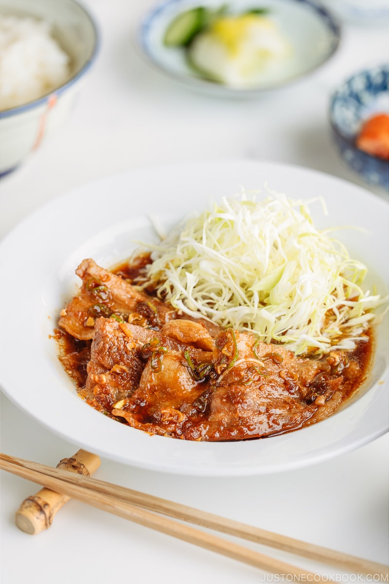 A plate containing Pan-Fried Ginger Pork Belly along with shredded cabbage.