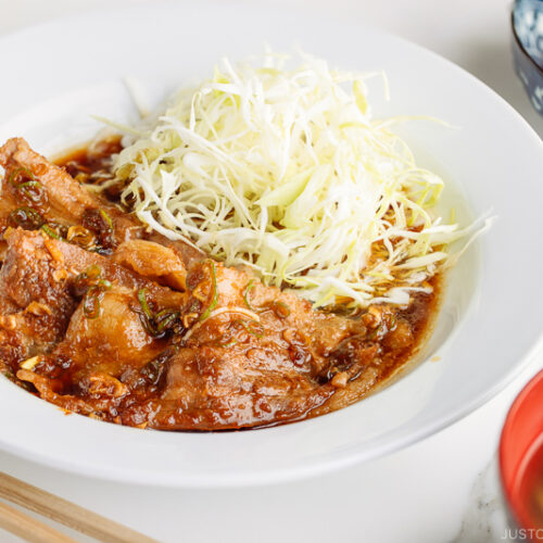 A plate containing Pan-Fried Ginger Pork Belly along with shredded cabbage.