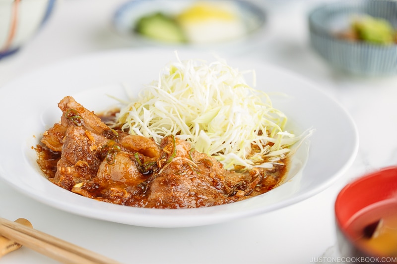 A plate containing Pan-Fried Ginger Pork Belly along with shredded cabbage.