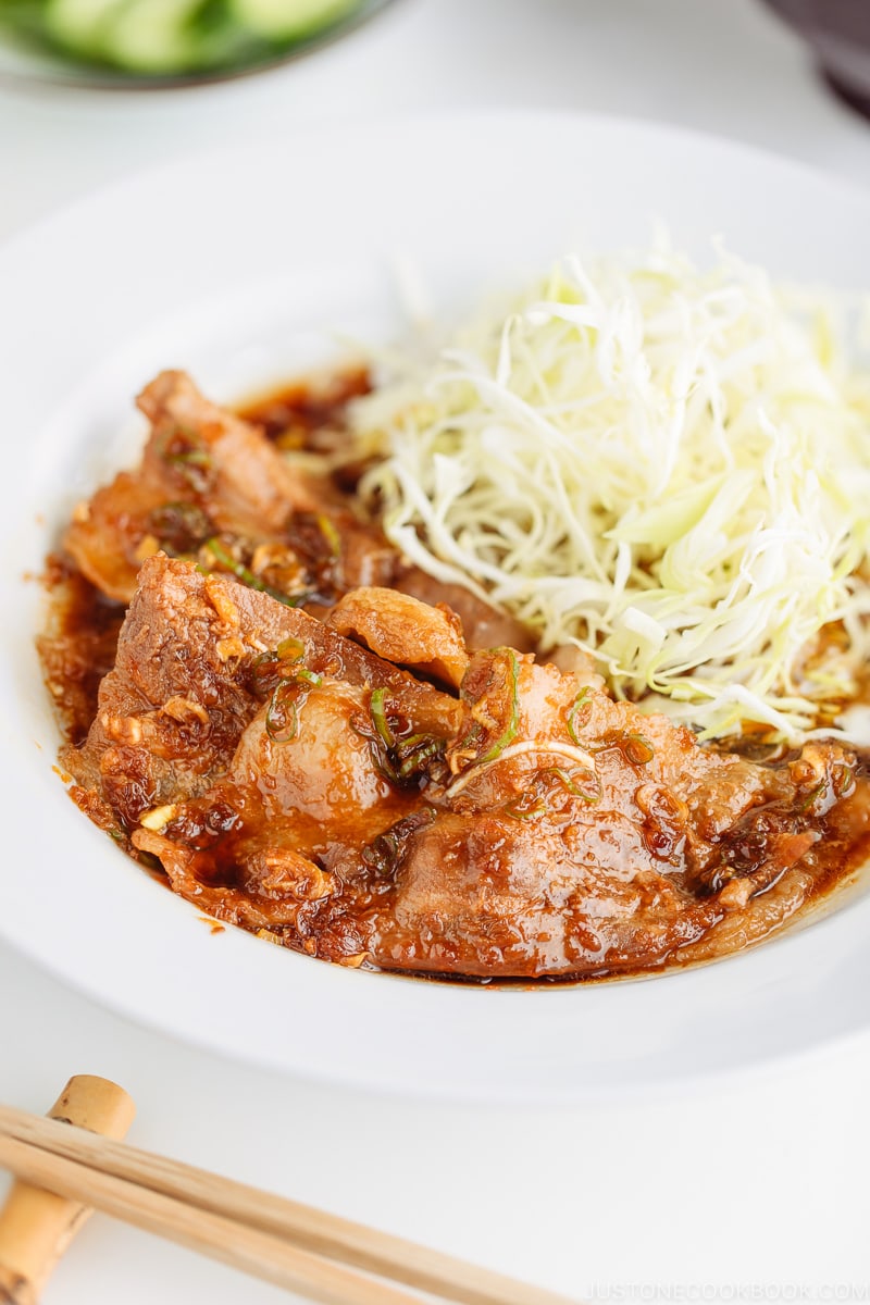 A plate containing Pan-Fried Ginger Pork Belly along with shredded cabbage.