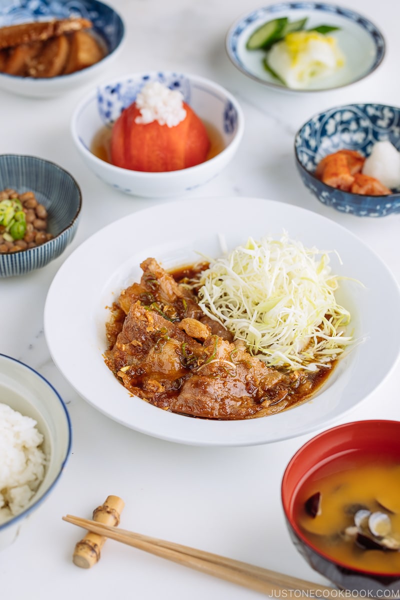 A plate containing Pan-Fried Ginger Pork Belly along with shredded cabbage.