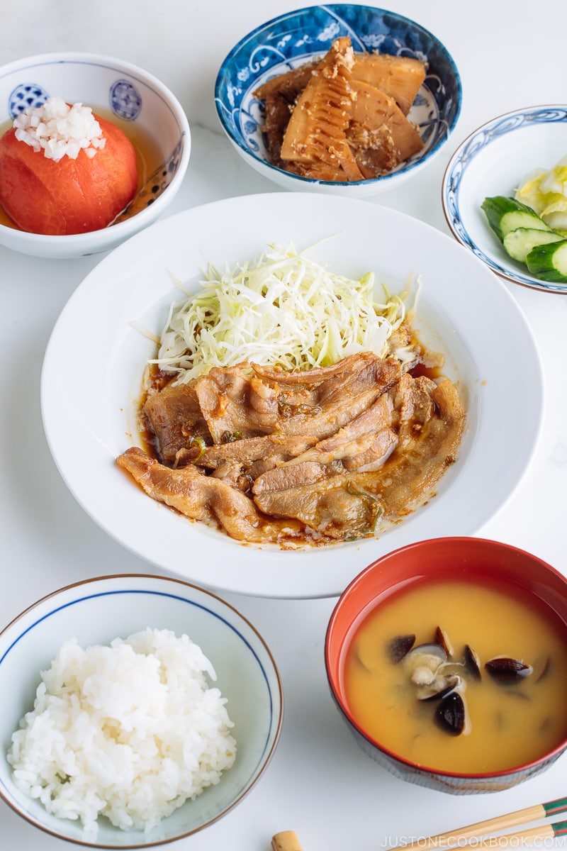 A plate containing Pan-Fried Ginger Pork Belly along with shredded cabbage.