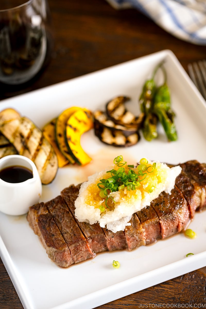 A plate containing Japanese-Style Sous Vide Steaks topped with greated daikon and ponzu sauce.