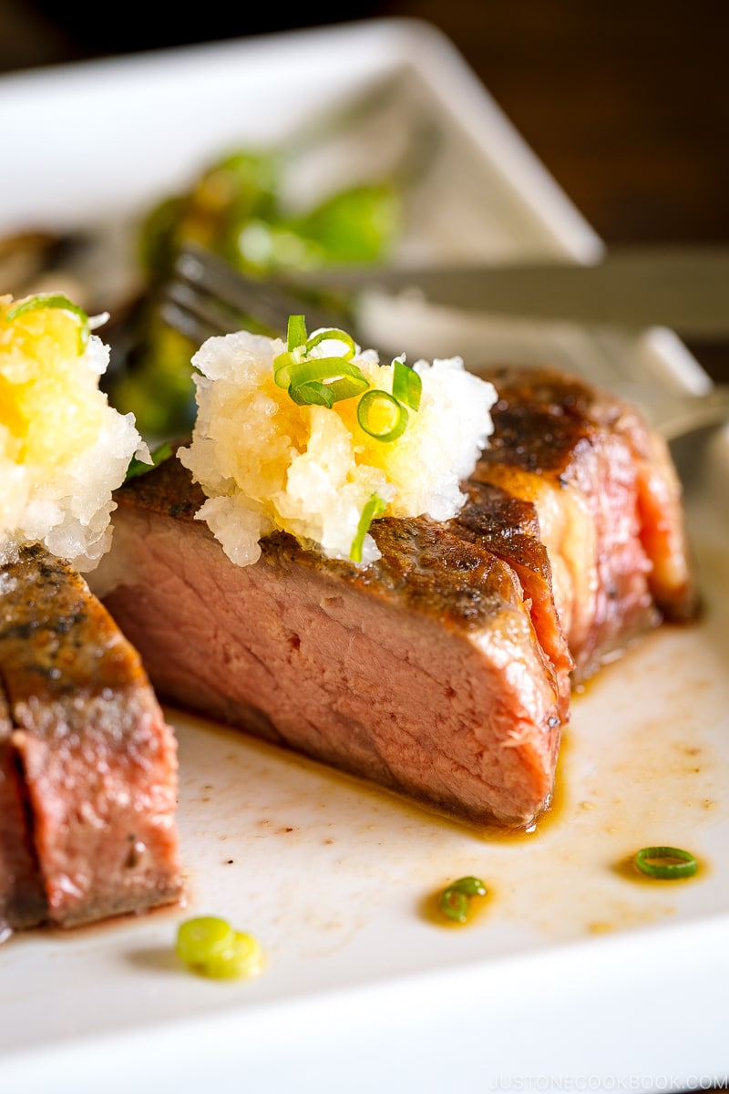 A plate containing Japanese-Style Sous Vide Steaks topped with greated daikon and ponzu sauce.