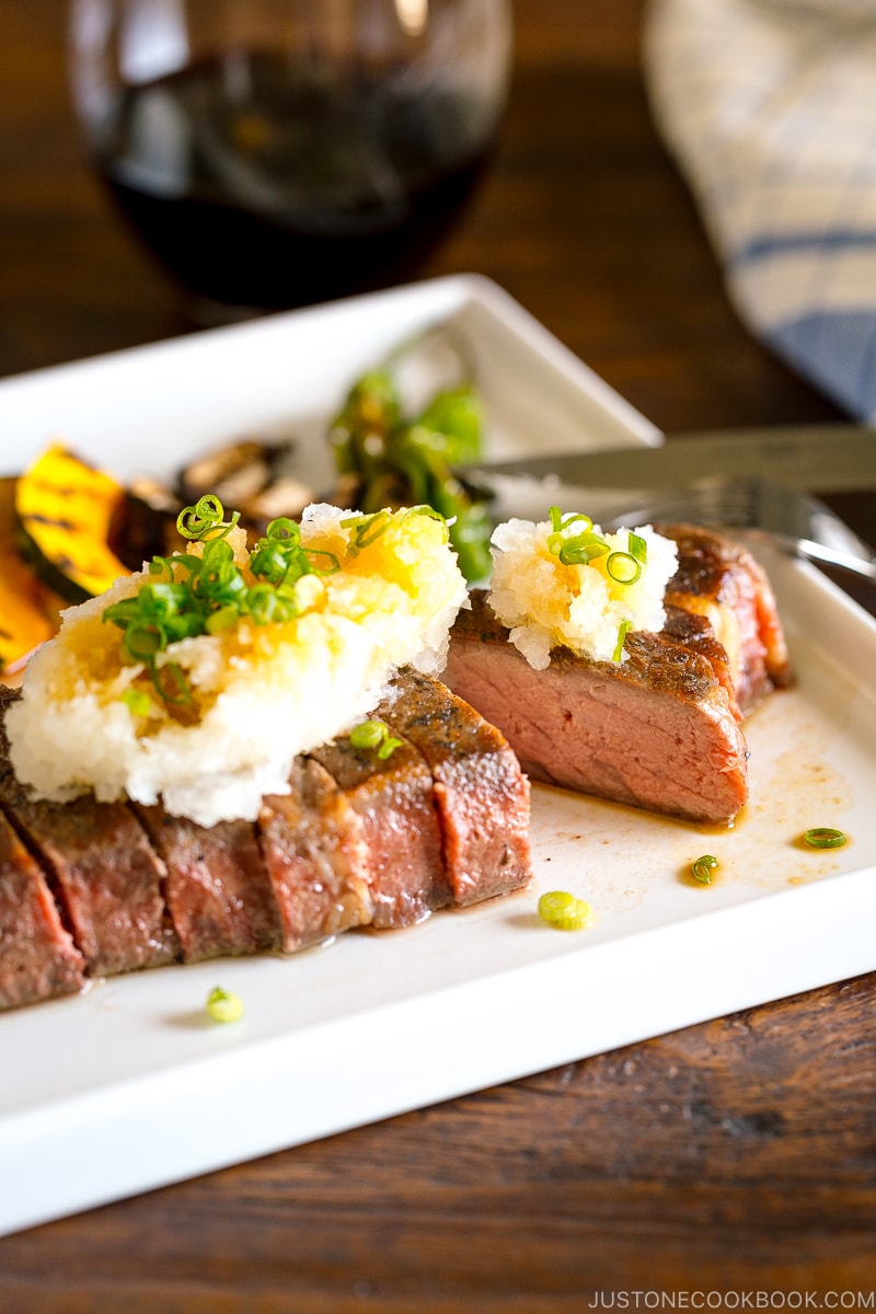 A plate containing Japanese-Style Sous Vide Steaks topped with greated daikon and ponzu sauce.