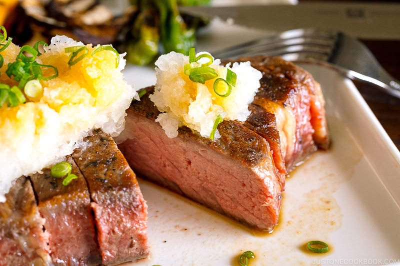 A plate containing Japanese-Style Sous Vide Steaks topped with greated daikon and ponzu sauce.