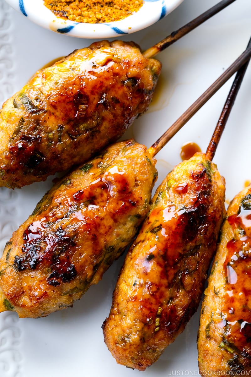 A white plate containing Tsukune (Japanese Chicken Meatball Skewers).