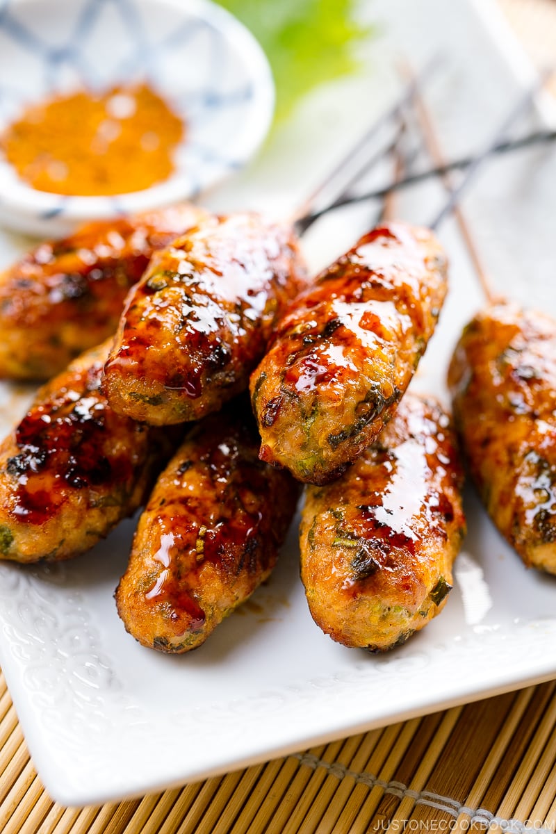 A white plate containing Tsukune (Japanese Chicken Meatball Skewers).