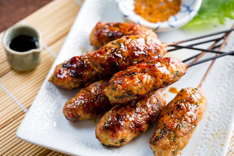 A white plate containing Tsukune (Japanese Chicken Meatball Skewers).