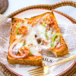 A plate containing Japanese Pizza Toast made with Japanese milk bread, pizza sauce, mozzarella cheese, and various toppings.