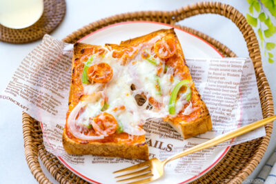 A plate containing Japanese Pizza Toast made with Japanese milk bread, pizza sauce, mozzarella cheese, and various toppings.