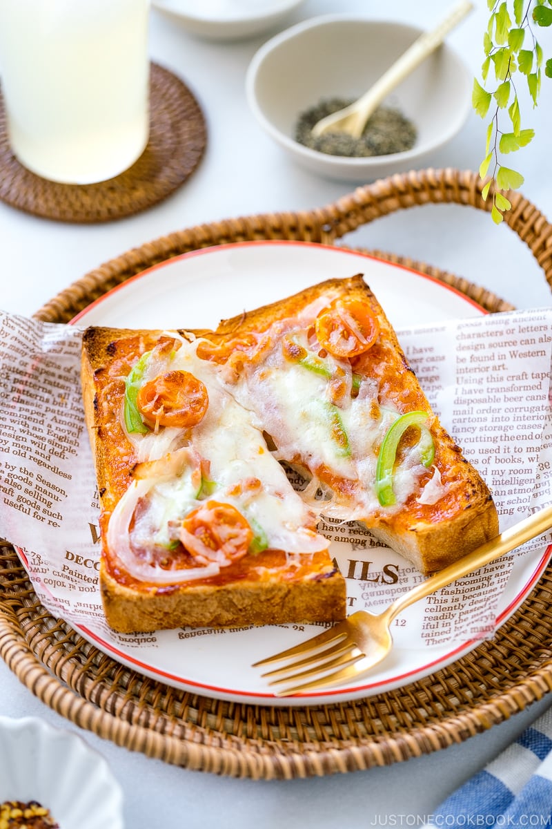 A plate containing Japanese Pizza Toast made with Japanese milk bread, pizza sauce, mozzarella cheese, and various toppings.