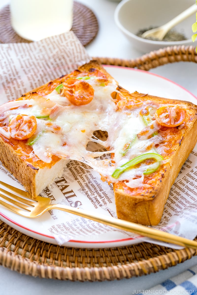 A plate containing Japanese Pizza Toast made with Japanese milk bread, pizza sauce, mozzarella cheese, and various toppings.