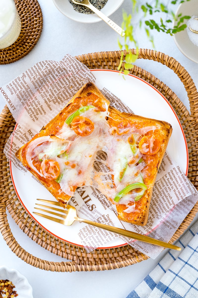 A plate containing Japanese Pizza Toast made with Japanese milk bread, pizza sauce, mozzarella cheese, and various toppings.