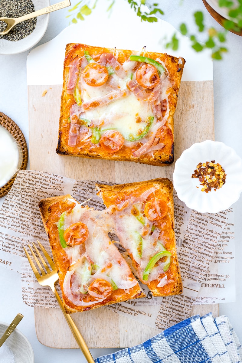 A plate containing Japanese Pizza Toast made with Japanese milk bread, pizza sauce, mozzarella cheese, and various toppings.