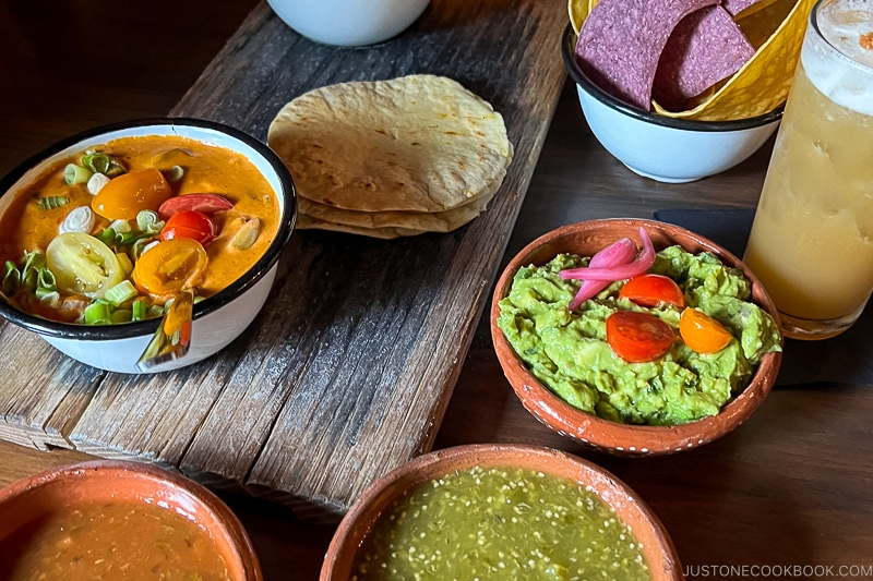 Queso Fundido and guacamole on a table next to salsa