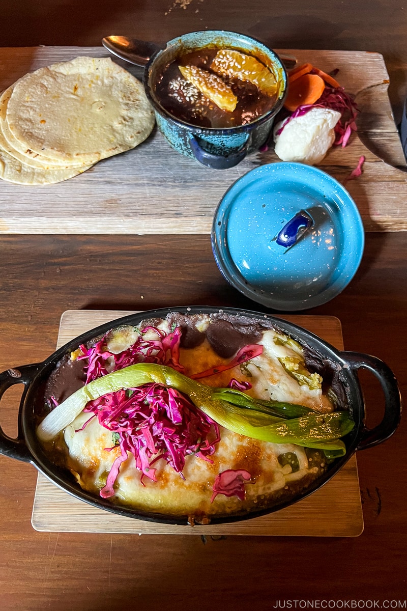 Cultura mole and chicken enchiladas on a wood table