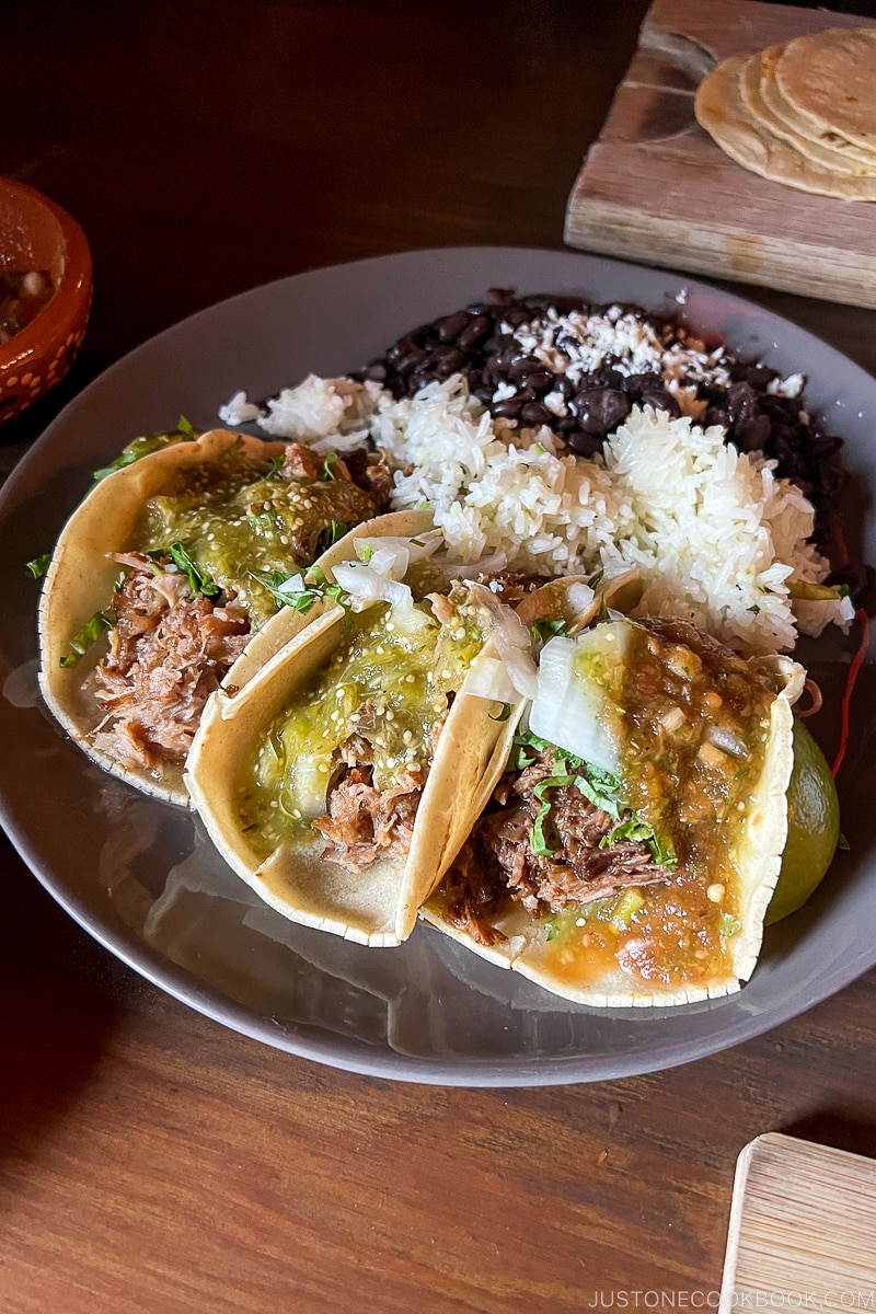 three tacos with rice and beans on a plate