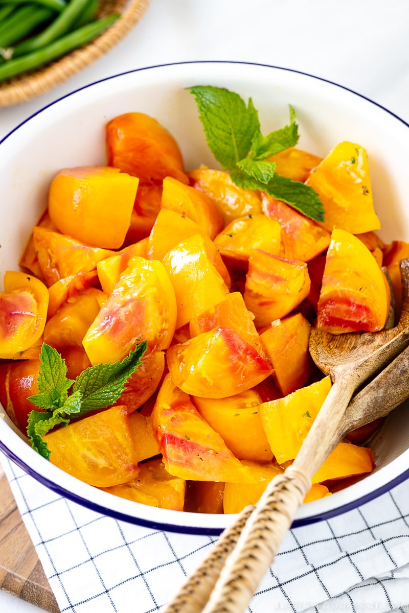 A white enamel bowl containing Heirloom Tomato Salad garnished with mint.