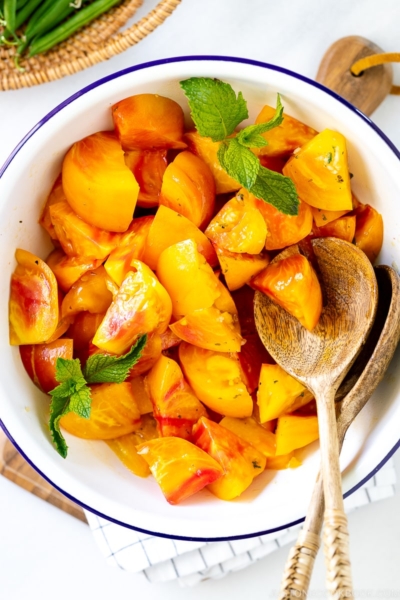 A white enamel bowl containing Heirloom Tomato Salad garnished with mint.