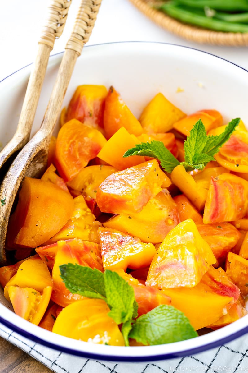 A white enamel bowl containing Heirloom Tomato Salad garnished with mint.