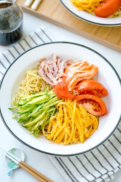 A white plate containing cold ramen (Hiyashi Chuka) with julienned cucumber, ham, egg, and more!