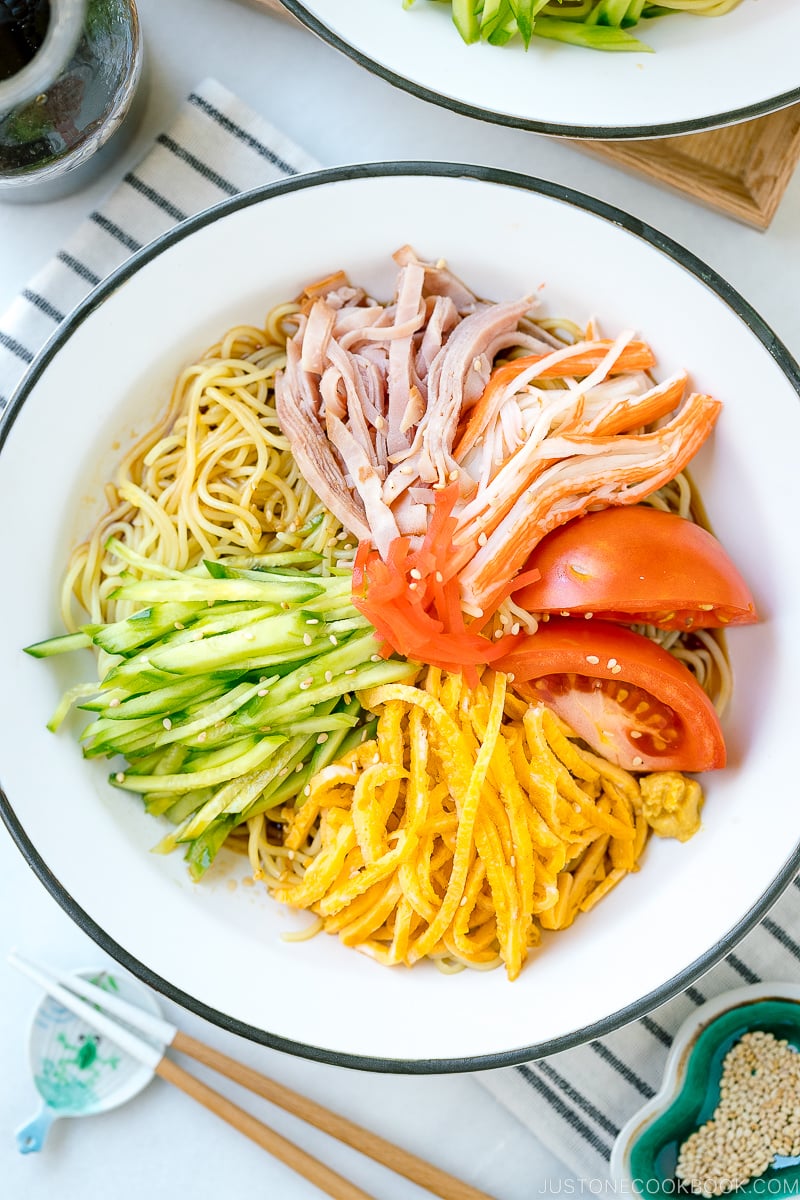 A white plate containing cold ramen (Hiyashi Chuka) with julienned cucumber, ham, egg, and more!