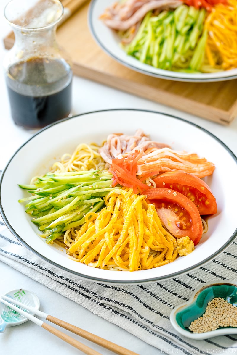 A white plate containing cold ramen (Hiyashi Chuka) with julienned cucumber, ham, egg, and more!