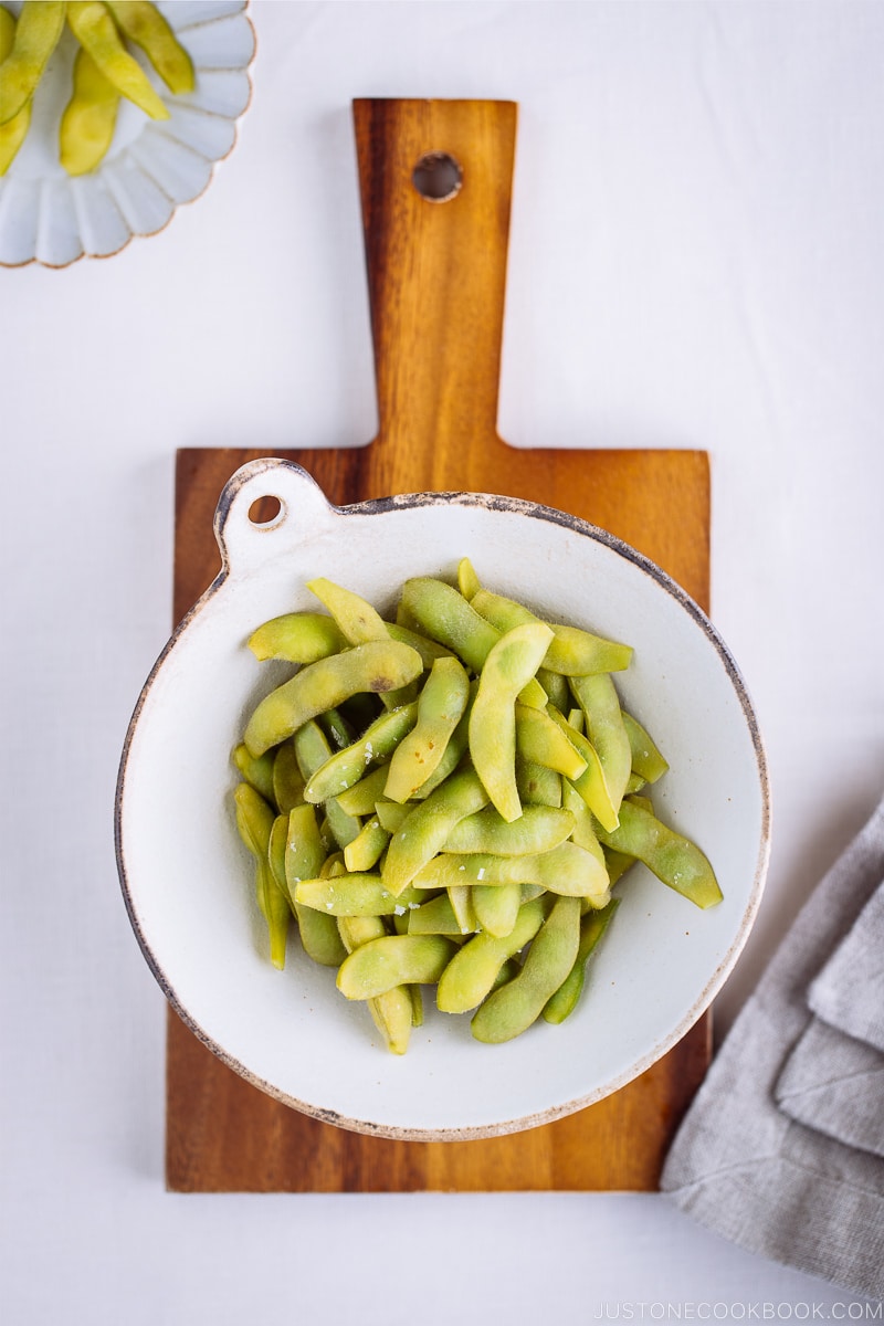 A ceramic bowl containing perfectly cooked and salted edamame.