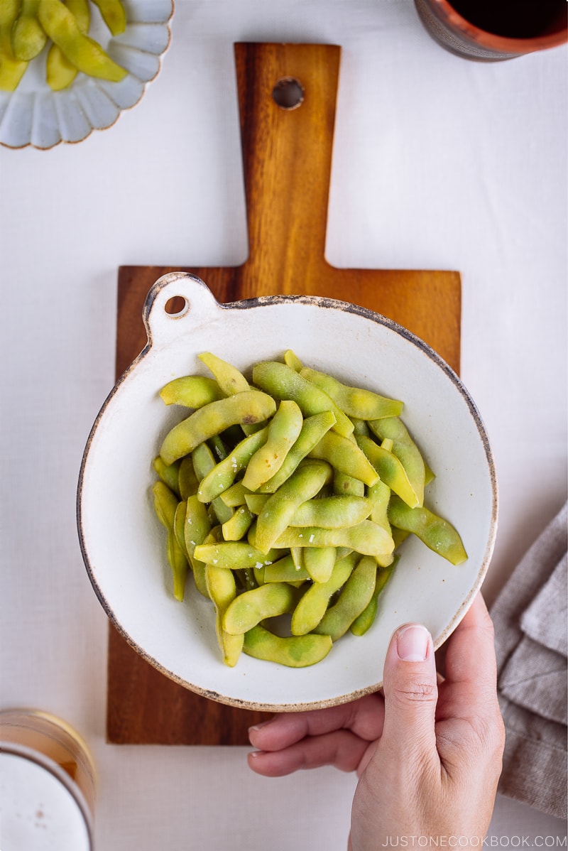 A ceramic bowl containing perfectly cooked and salted edamame.