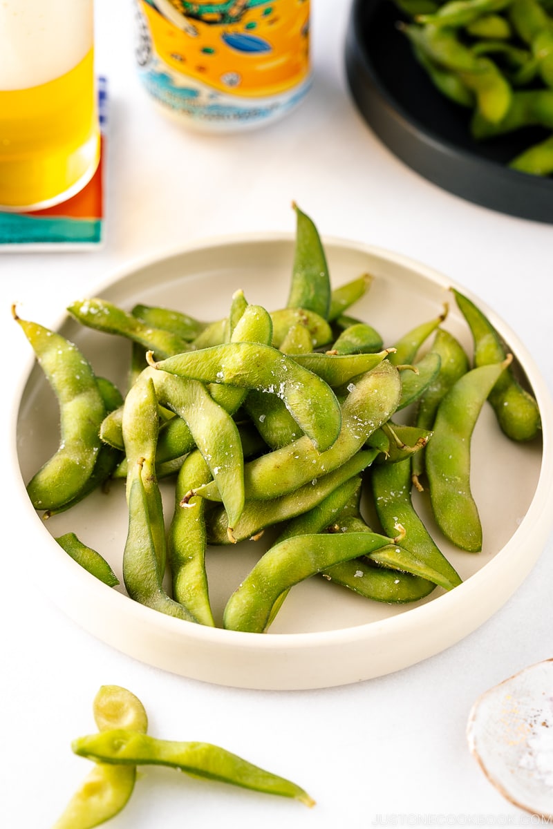 A white ceramic plate containing Edamame.