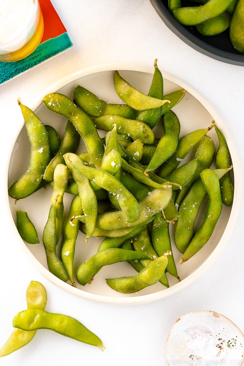 A white ceramic plate containing Edamame.