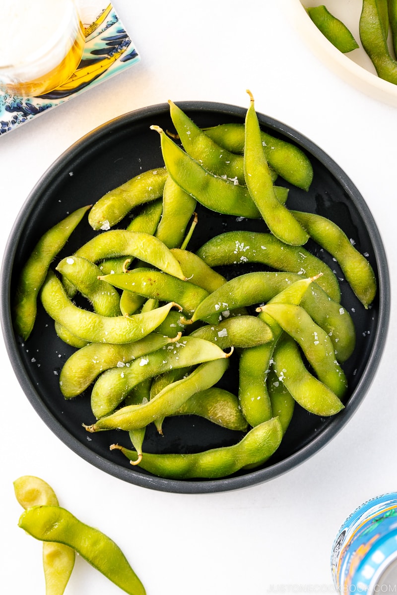 A black ceramic plate containing Edamame.